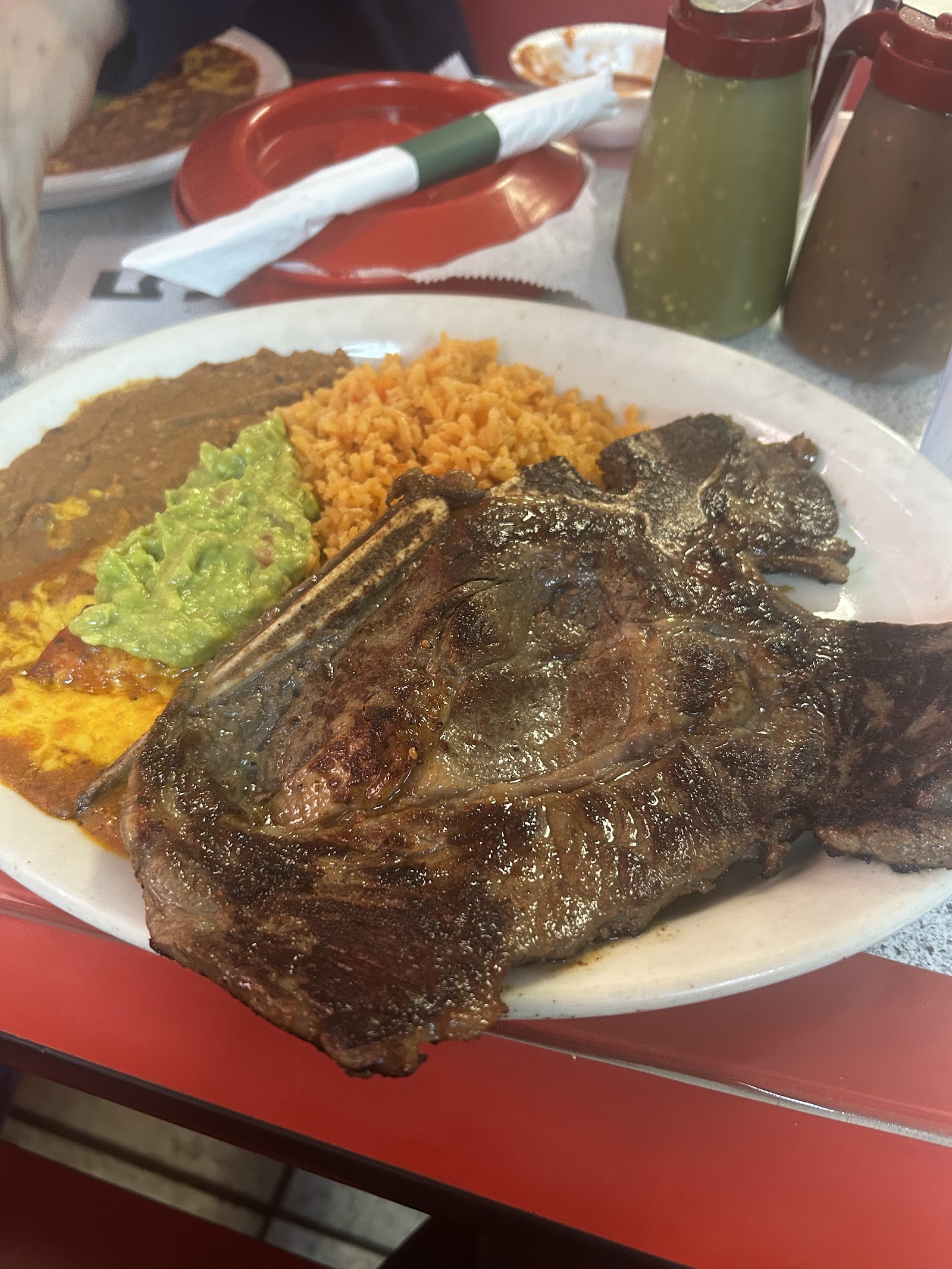 Grilled T-bone steak plate with rice, beans and guacamole
