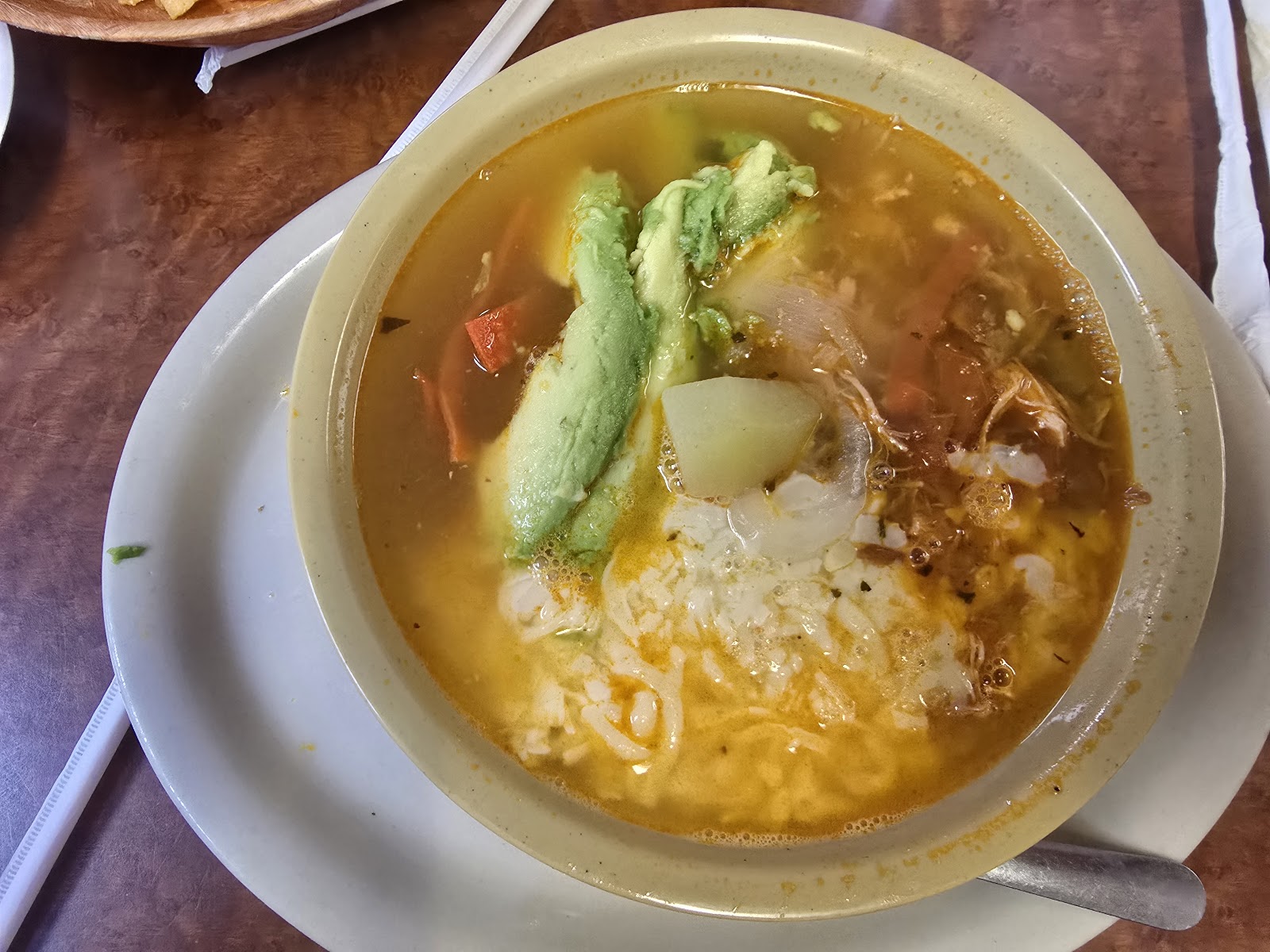 Bowl of tortilla soup with avocado and potato